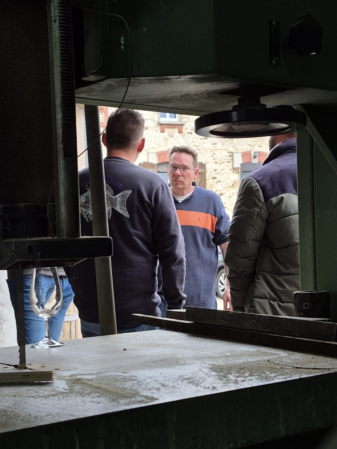 Verre gravé et échange dans l'atelier, vue à travers le pressoir ancien